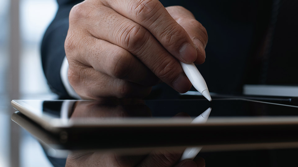 Man's hand using pen to write on tablet