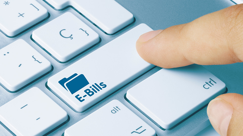 A finger touching a key that says "E-Bills" on a keyboard