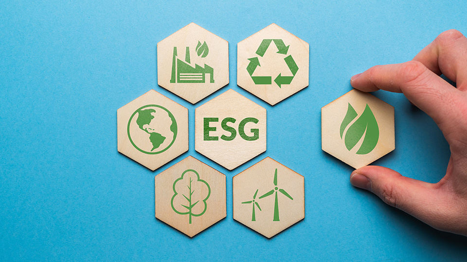 a hand place hexagonal blocks with images on them related to ESG or environmental social governance over a blue background