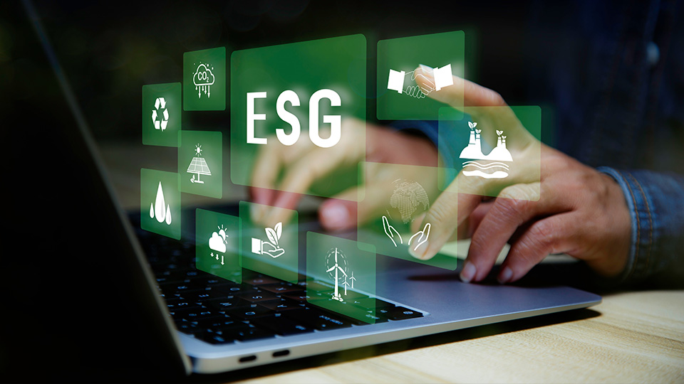Hands on a laptop keyboard with green holographic boxes above with ESG and icons representing ESG concepts.