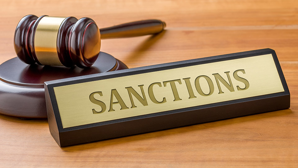 a gavel and nameplate with the word "Sanctions" on a desk