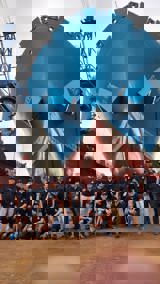 Group of people gathered in front of the bow of a ship in dry dock