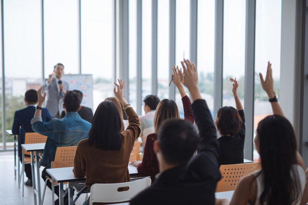 people in a classroom with their hands raised