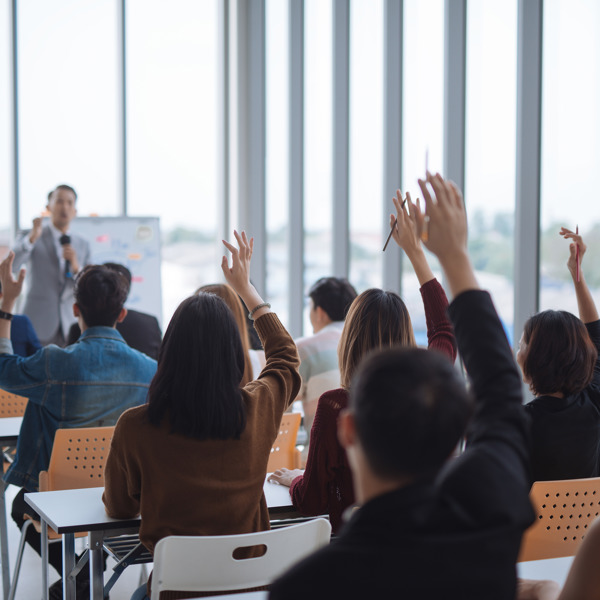 people in a classroom with their hands raised