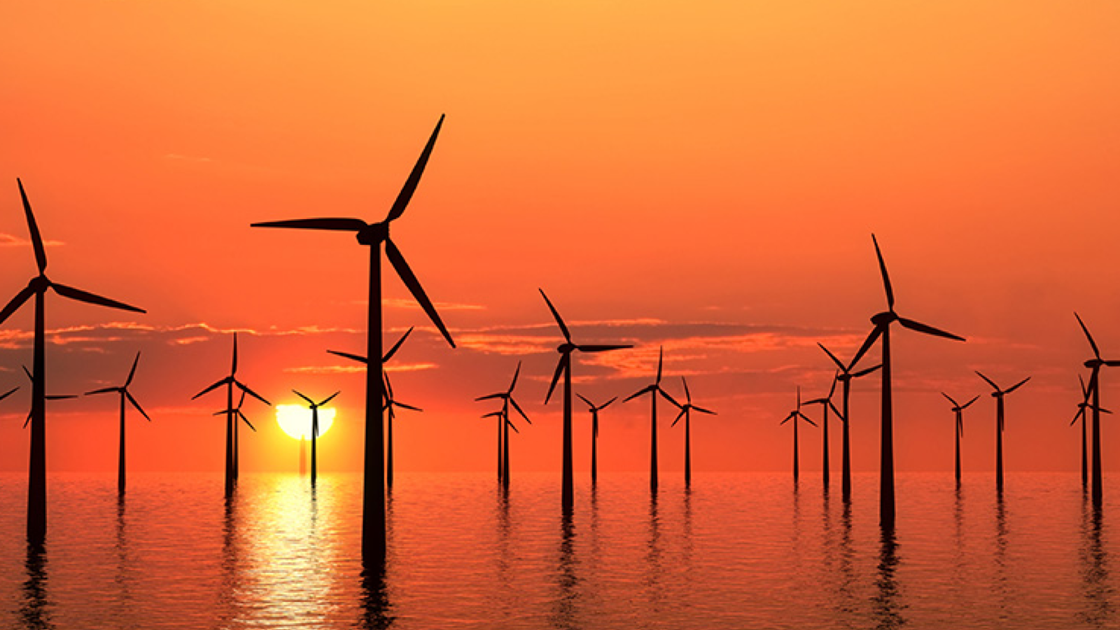 An offshore windfarm with many wind turbines against a colourful sunset background