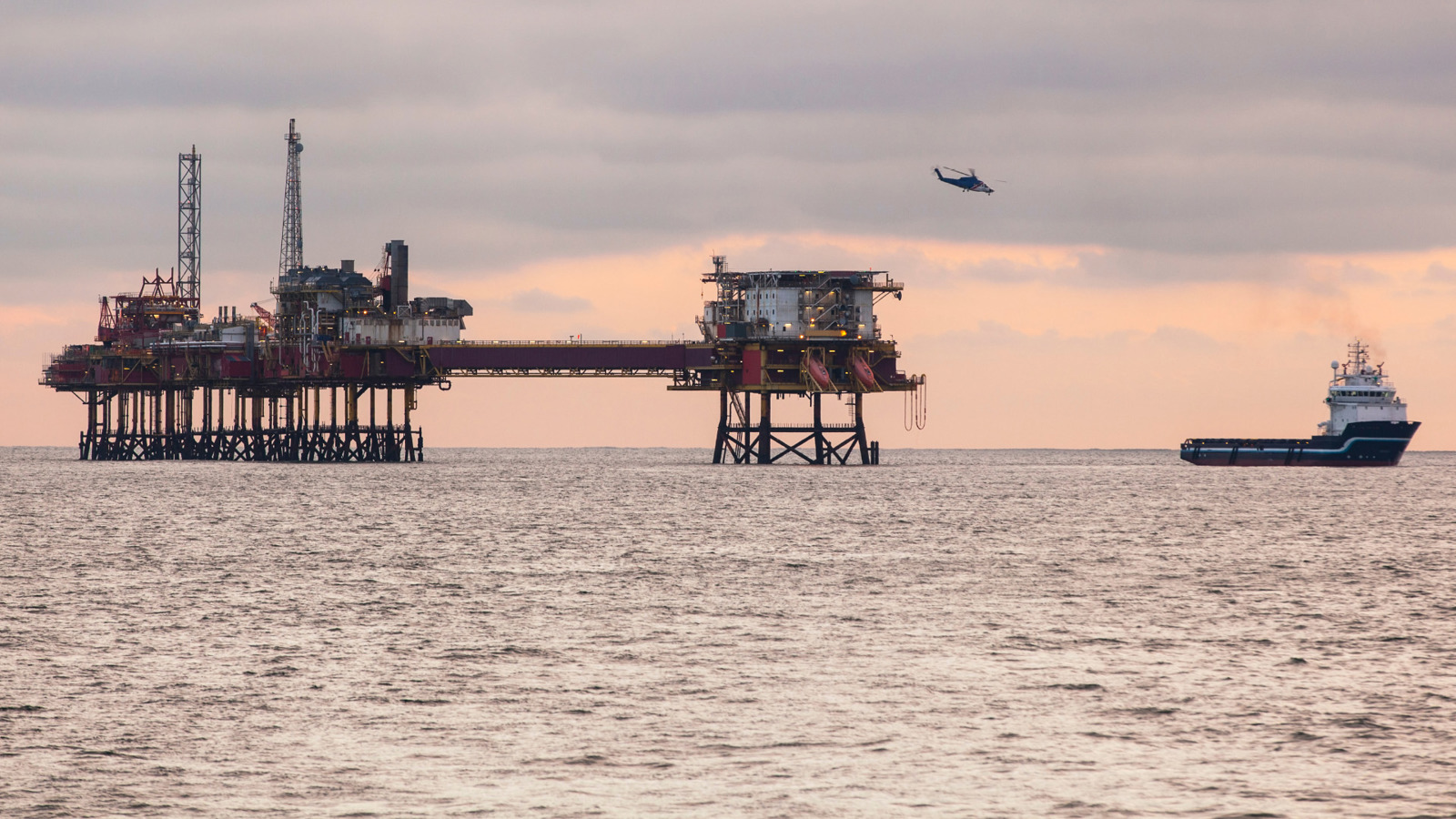 Supply vessel moving away from an offshore construction platform for oil and gas production 