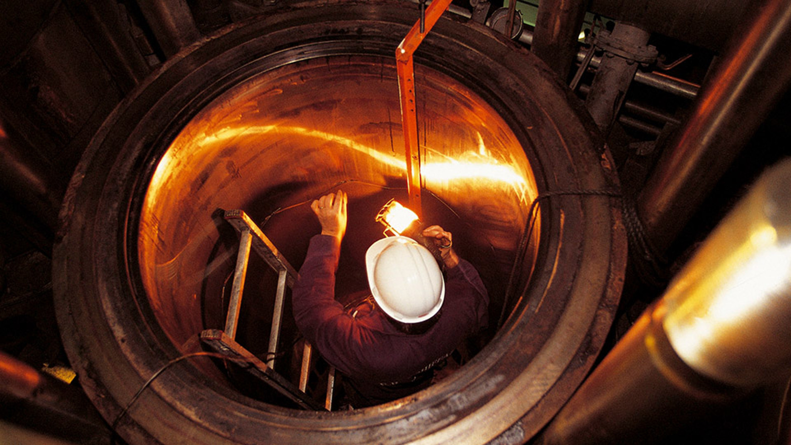 Man going down a ladder of an enclosed space on a ship