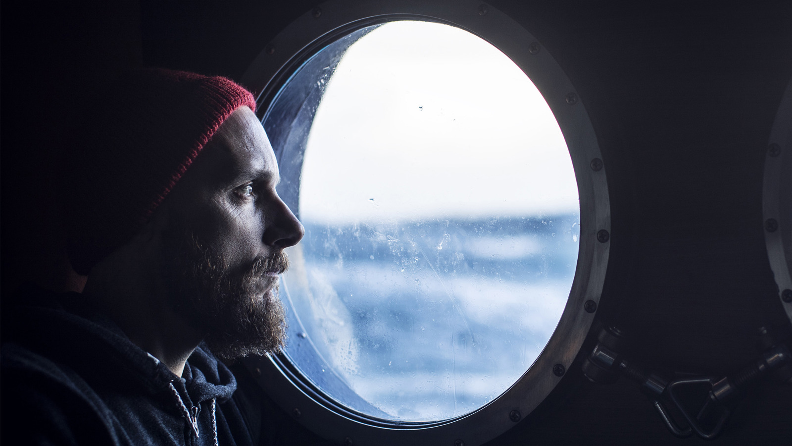 A seafarer looking out of a ship's porthole