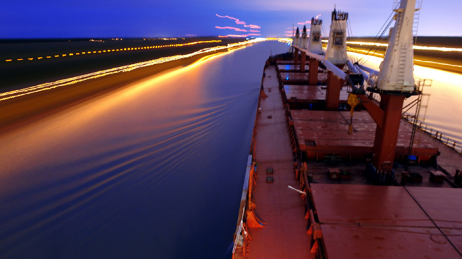 red bulker ship navigating a canal