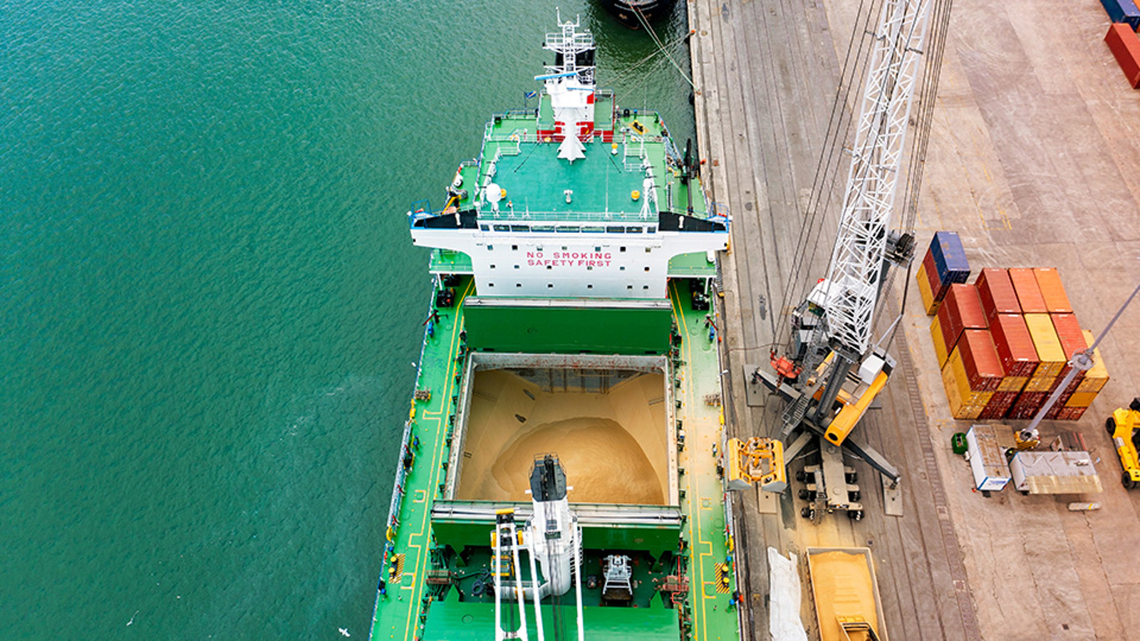 Aerial view of a green cargo ship loading grain
